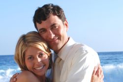 A beautiful woman hugs a man and smiles at the beach