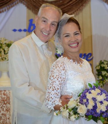 White man standing behind his beautiful Asian wife, who is smiling with joy after marrying