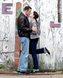 A couple kisses next to a building