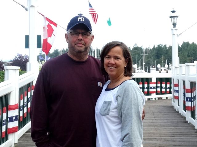 Patriotic flags in background with couple smiling on harbor walkway