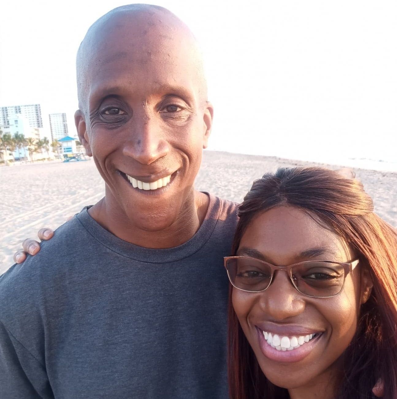 A Christian couple laugh at the beach while posing for a selfie