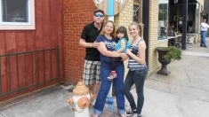 A family pose on a sidewalk next to a storefront