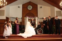 A couple marry on a church stage, flanked by their wedding party