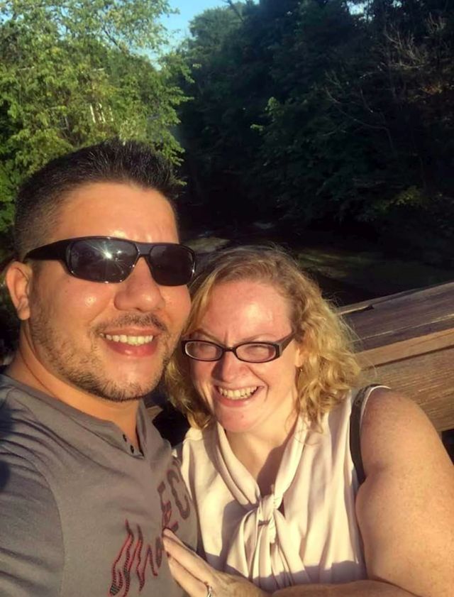 A loving Christian couple laughing while posing together on a hike in the sunshine