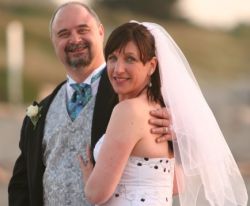 A man leans back and laughs while hugging a woman who looks pleased to be with him