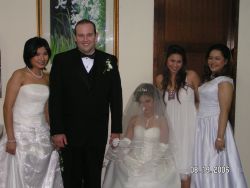 Flower girl in veil holds groom's hand while his bride unveiled holds the other