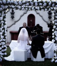 A married couple sit and receive their blessing at their wedding