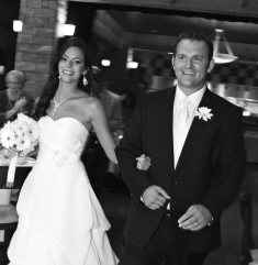 A triumphant looking bride and groom enter a room arm in arm