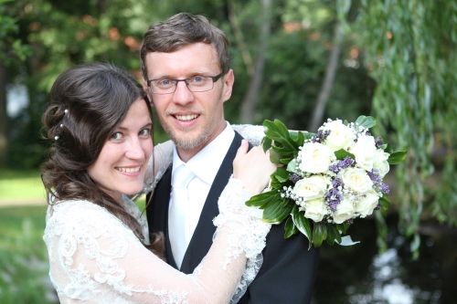 A woman hugs a man and prepares to kiss him, while smiling at the camera