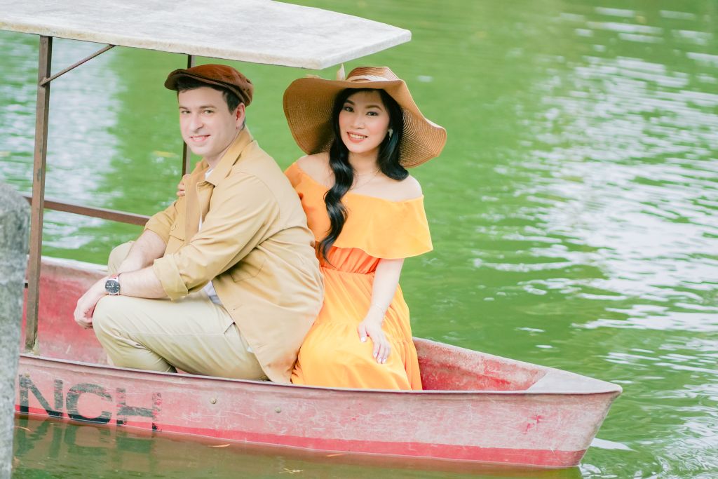 A White Christian man sits in a boat on a lake with a beautiful Filipina woman