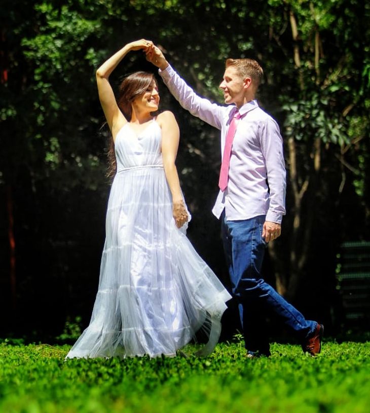 A man holds the hand of a beautiful woman who dances in the grass