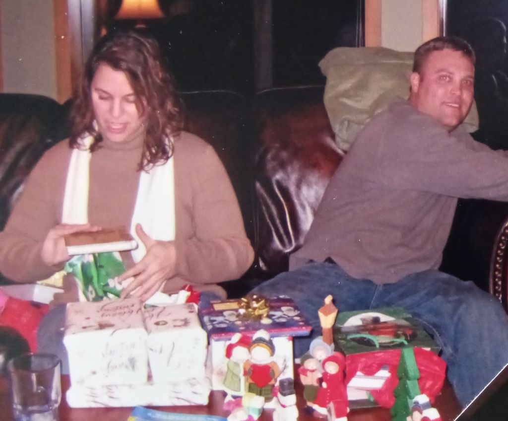A Christian woman opens a gift on Christmas Day while he husband laughs in the background