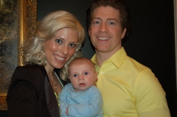 Cute baby stares inquisitively at camera while his proud young parents laugh