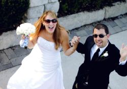 An ecstatic bride and groom from Michigan wave to the camera above after marrying