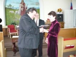 A man and woman laugh as her puts a ring on her finger