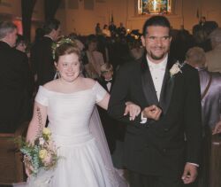 Man rushes out of reception hall with his new bride who laughs