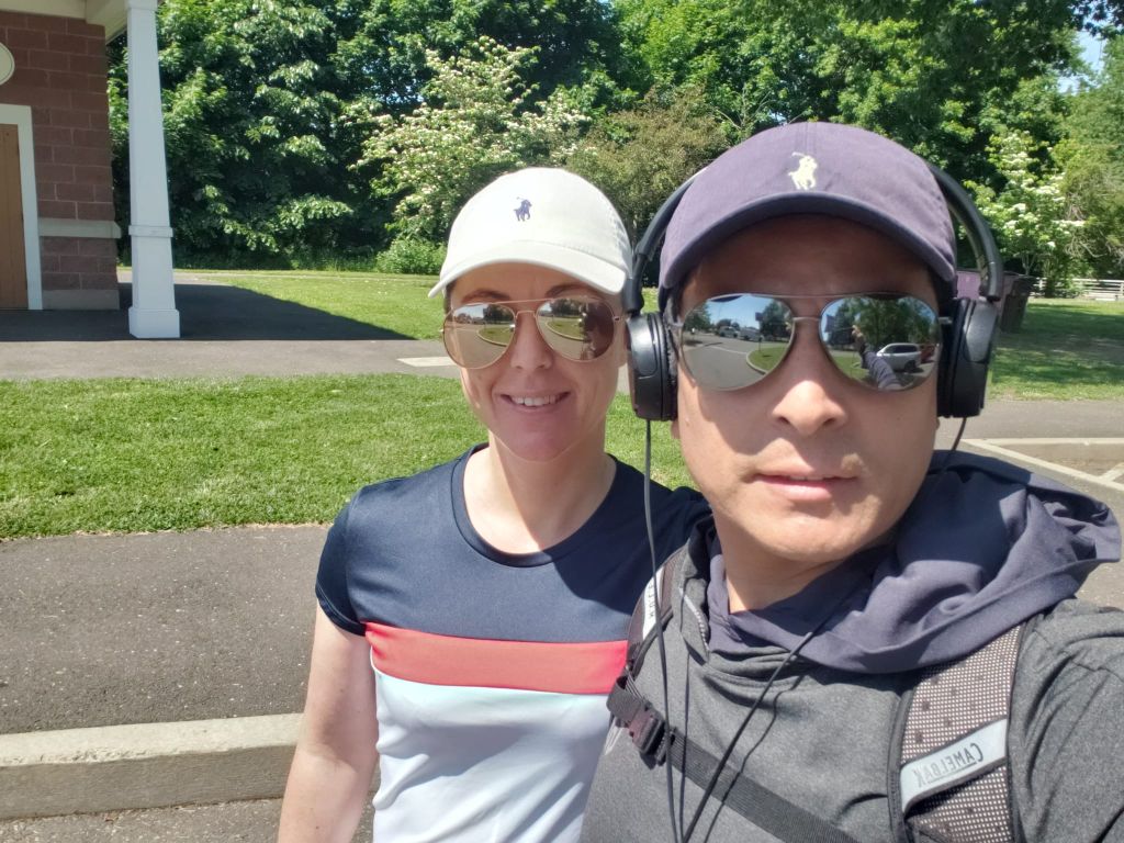 Christian singles in athletic wear and sporting sunglasses and ball caps take a selfie while out for a walk in the city