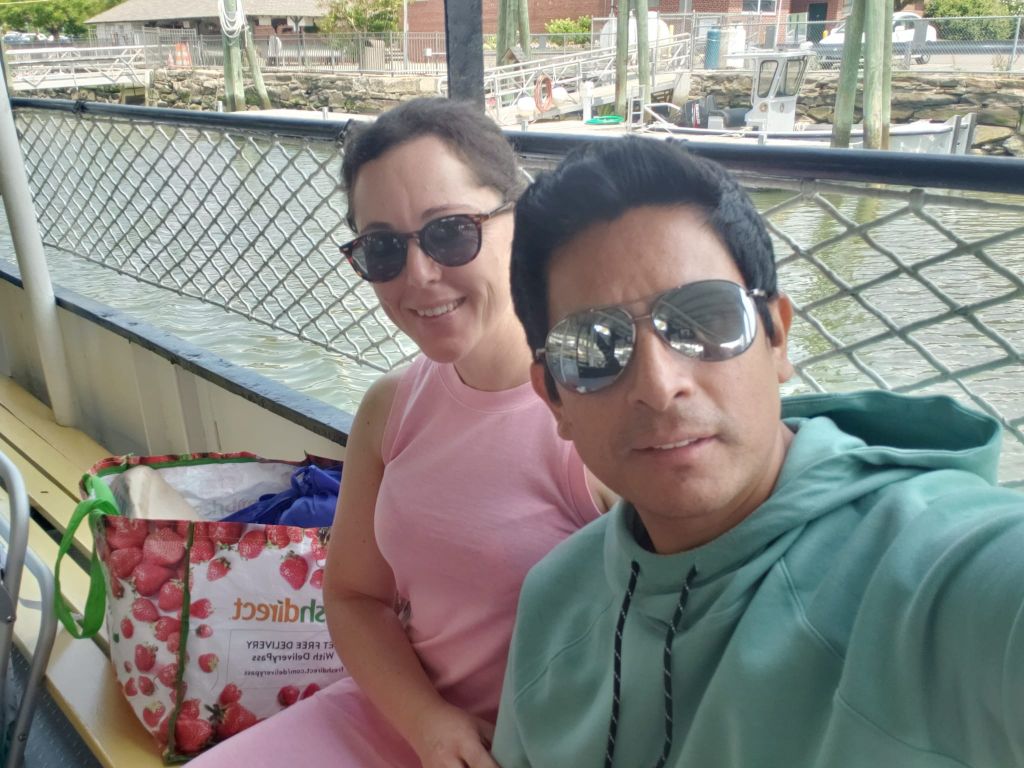 A couple are seated side by side on a boat in a canal after shopping