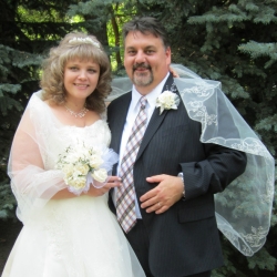 A woman can hardly contain her joy as she stands in her wedding dress next to her husband who is laughing