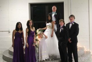 Bride and groom stand in between beautiful bridesmaids and handsome groomsmen