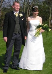 A beautiful bride looks very happy as she stands next to her new husband