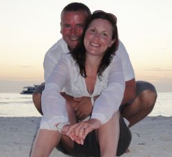 Newly engaged Christian couple laugh and hug together at a beach sunset