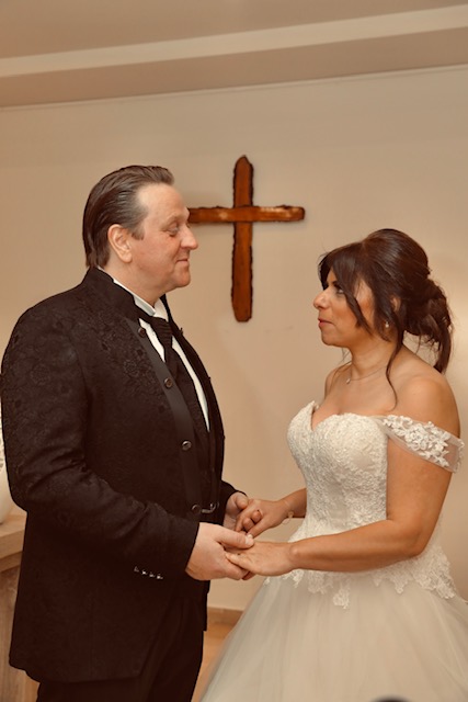 A beautiful Middle Eastern Christian woman in her bride's dress looks lovingly in her new husband's eyes while he holds her hands on their wedding day