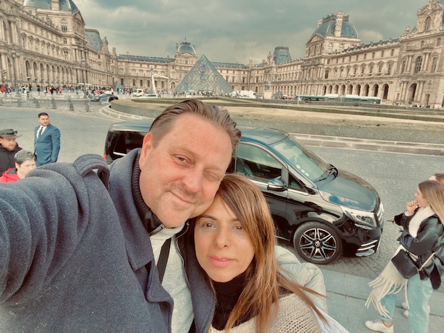 An attractive couple take a selfie in Paris outside the Louvre museum