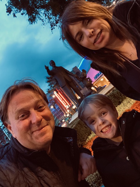 A Christian family poses at night near a statue of Walt Disney and Mickey Mouse at Disneyland Paris