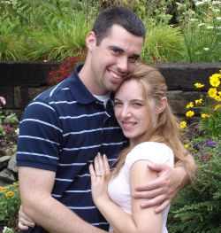 Proposal in rose garden as man hugs his beautiful fiancee