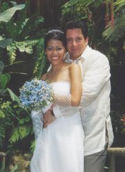 A man lovingly hugs his bride from behind as she smiles