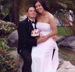 Christian bride sits on her groom's knee as he hugs her tightly