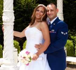 A Christian military man looks overjoyed to be holding his beautiful new bride as she smiles