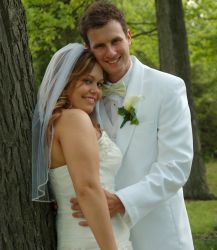 A beautiful American Christian woman hugged by her Canadian Christian husband near a tree