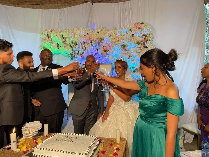 A group of wedding guests toast the bride and groom over a wedding cake