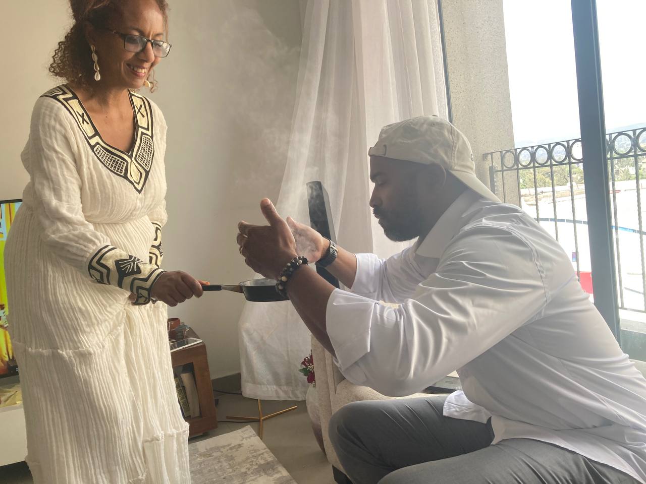 A new bride roasts Ethiopian coffee beans and holds the smoking pan to her new husband, who smells the flavoured smoke