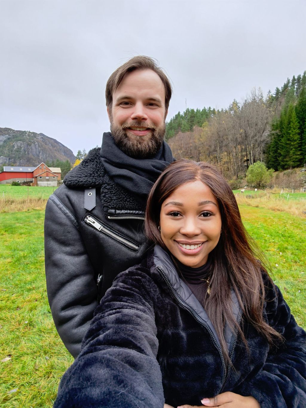 A beautiful African Christian woman in Norway smiles in front of a smiling bearded Caucasian man