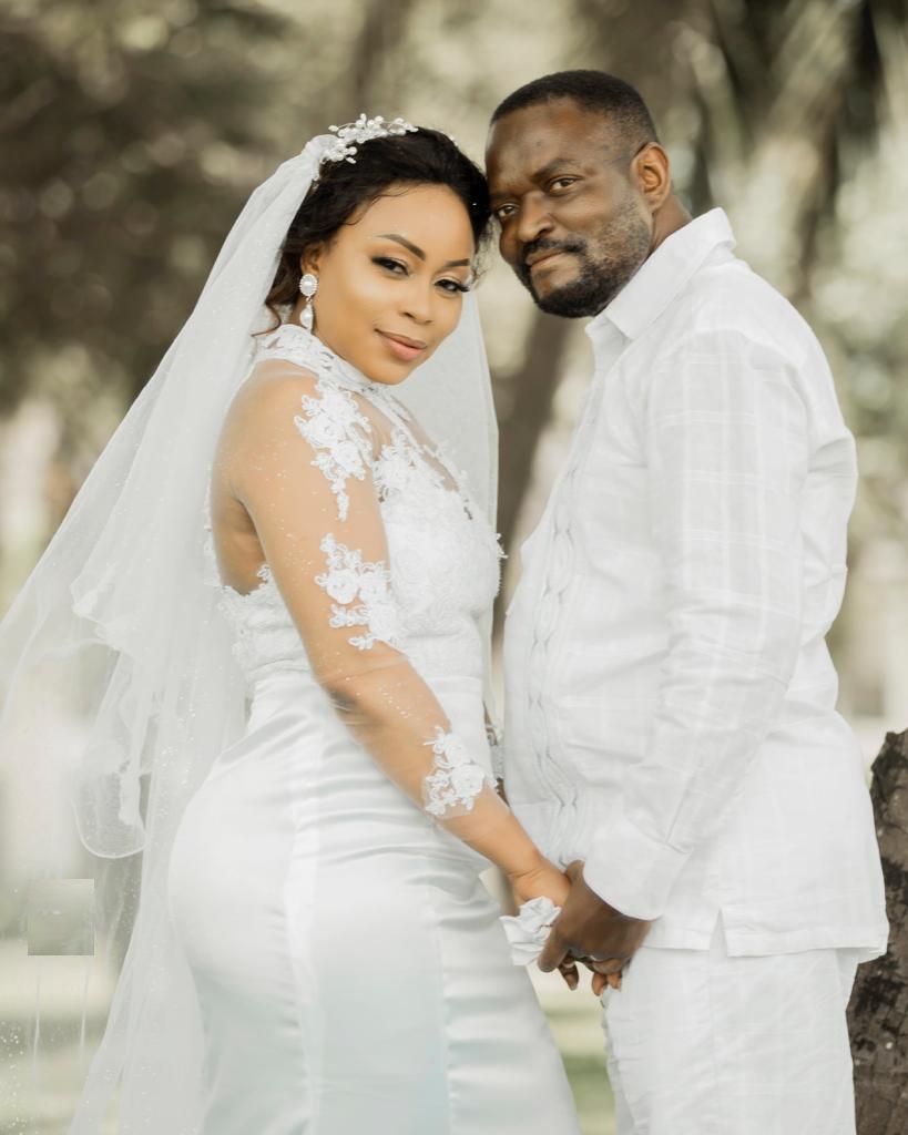 Christian couple dressed all in white hold hands while looking at camera