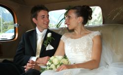 English Christian couple laugh together in their wedding car