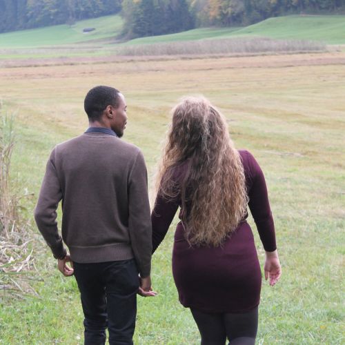 Christian couple meets in Switzerland and hold hands as they walk into beautiful countryside