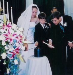 Christian singles meet at church and marry. Shown here on their wedding day behind beautiful flowers