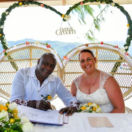 Former Christian singles now married, smiling and signing register at tropical wedding