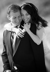 A woman laughs and is the picture of comfort as she hugs a man from behind