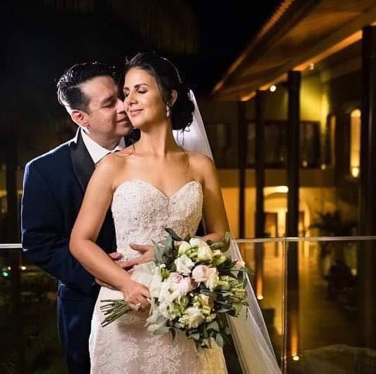 A groom lovingly kisses his bride's neck as she holds her flowers and closes her eyes