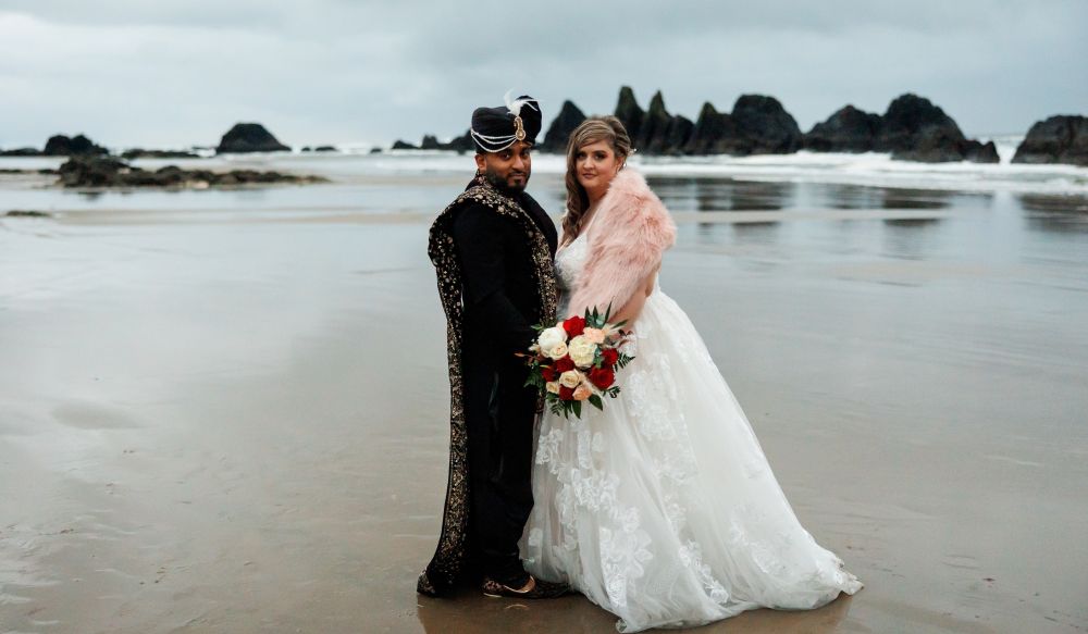 A Christian couple pose in traditional wedding clothes on the beach