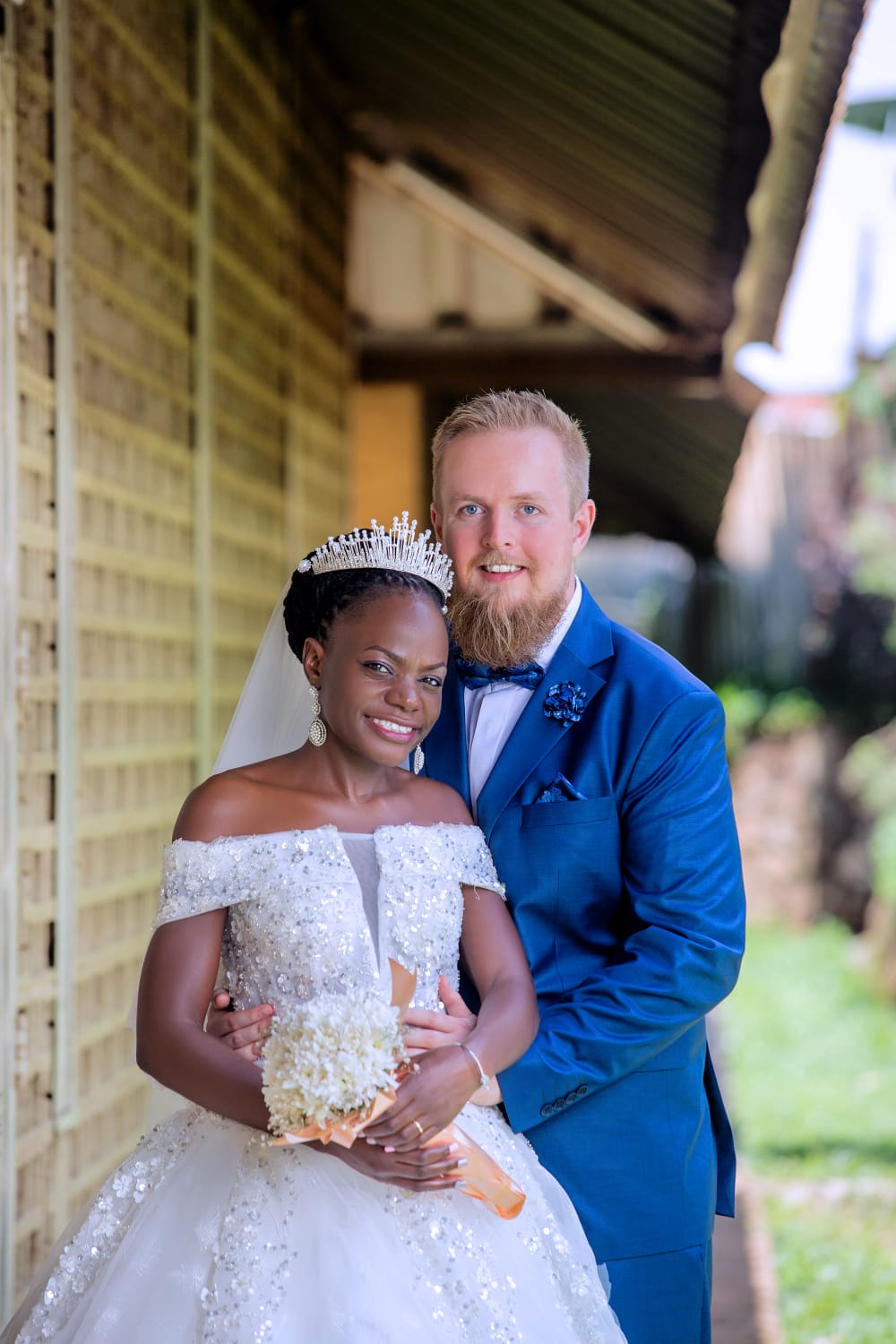A young attractive interracial Christian couple pose outdoors on their wedding day