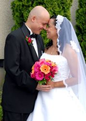 Groom leans in for a kiss from his smiling bride who holds flowers