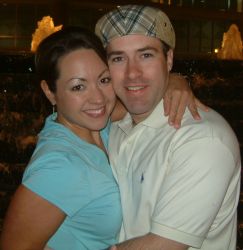 A beautiful woman hugs a man wearing a cap