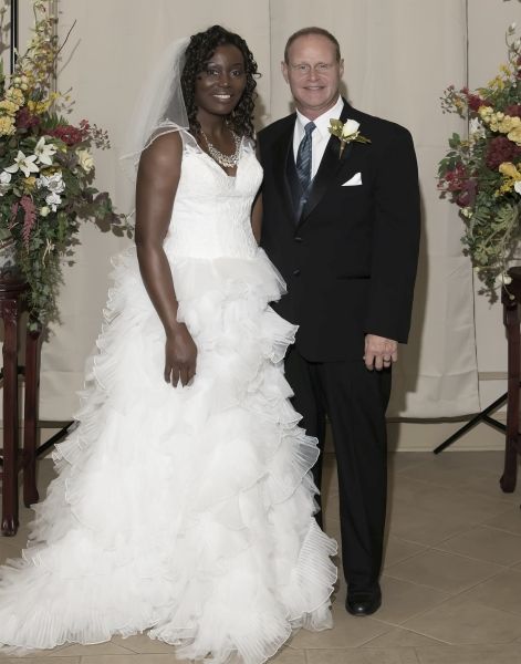 Smiling couple after marrying and flanked by beautiful arrangement of flowers