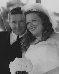 Tom and Stacy smile together on their wedding day near a pond